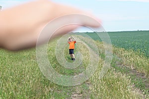 Big hand shelter little tiny boy in field