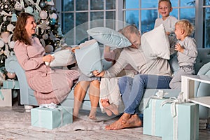 Big happy family with many kids having pillow fight under the Christmas tree on Christmas eve