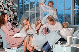 Big happy family with many kids having pillow fight under the Christmas tree on Christmas eve