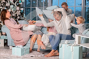 Big happy family with many kids having pillow fight under the Christmas tree on Christmas eve
