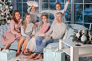 Big happy family with many kids having pillow fight under the Christmas tree on Christmas eve