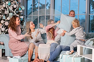 Big happy family with many kids having pillow fight under the Christmas tree on Christmas eve