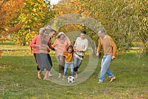 Big happy family playing football in autumn park