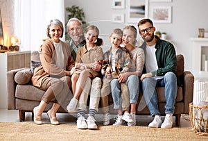 Beautiful multi generational family sitting together on couch at home and smiling at camera photo