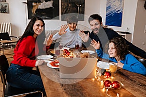 Big happy family using laptop while having christmas dinner at home