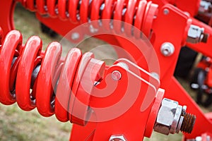 Big and hard red steel spring as part and detail of industrial or agricultural machine