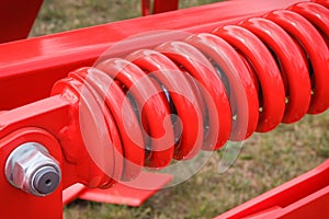 Big and hard red steel spring as part and detail of industrial or agricultural machine