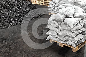 Big heap of dark black lump coal on floor bulk. Charcoal sorage at warehouse stock reserve. activated anthracite packed