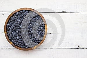 A big, heaping wooden bowl full of ripe, juicy blueberries