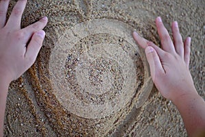 Big heart making by hands from the sand on the beach. Top view.