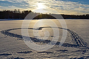 Big heart-shaped drawing on a frozen lake during sunset