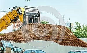 Big heavy construction machinery forklift transporting metal or steel reinforcement grid armature framework to building work site
