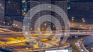 Big highway junction and Dubai water canal with pedestrian bridge over it aerial night timelapse.