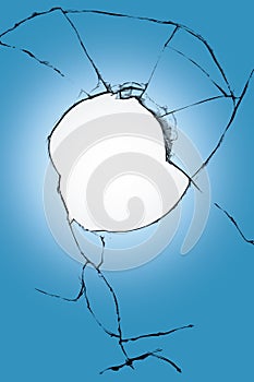 Big hole in window glass blue and white background background. Broken glass with cracks.