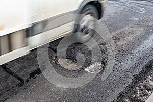 Big holes on asphalt road, passing blury car photo