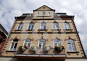 Big house with flowered balcony and large white windows in Bacharach along the Rhine Valley in Germany