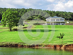 Big house with lawn next to lake