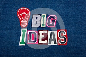 BIG IDEAS text word collage, multi colored fabric on blue denim, lightbulb, innovation concept