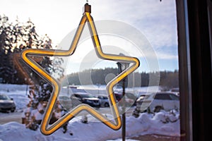 Big illuminated Christmas star on snowy pine tree in winter park at night, close up