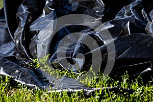 A big industrial black plastic dropped in a grass field.