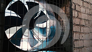 Big industrial fan in a white brick wall of a factory.