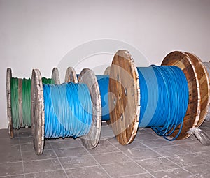 Big industrial wooden spools of blue and green wires on grey floor