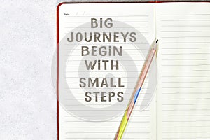 Big journeys begin with small steps on notebook with pencil isolated on gray background