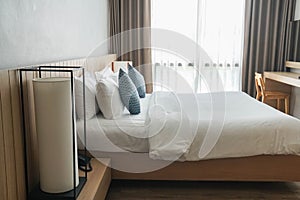 big lamp at bedside with white minimal double bed mattress in luxury hotel bedroom in silhouette view