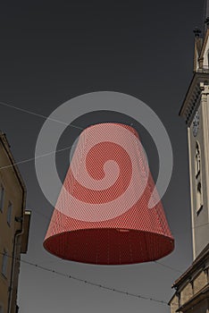 Big lamp with red shade over street in Villach city with gray background