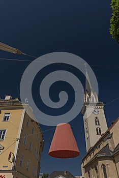 Big lamp with red shade over street in Villach city with gray background