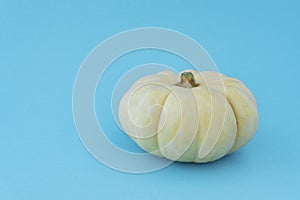 Big light yellow pumpkin on blue background, lot of copy space for text.