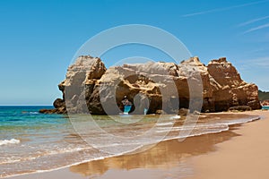 Big limestone rock with grottos washed by the ocean. Portimao, Portugal