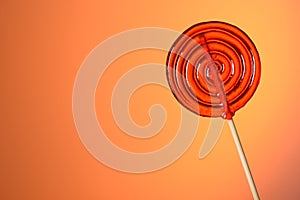 Big lollipop on wooden stick on warm orange background