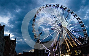 Big luminous ferris wheel in front of dark blue dramatic sky
