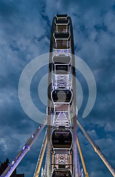 Big luminous ferris wheel in front of dark blue dramatic sky