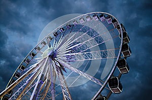 Big luminous ferris wheel in front of dark blue dramatic sky