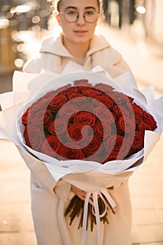 Big luxury bright bouquet of garden red roses in hands of cute girl