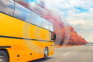 Big luxury comfortable tourist bus driving through golden autumn tree highway on bright sunny day. Blurred motion.Travel and coach