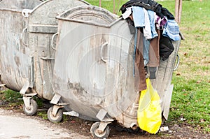 Big metal dumpster garbage cans full of overflow litter polluting the street in the city, environmental concept