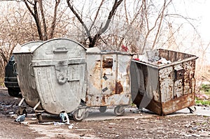 Big metal dumpster garbage cans full of overflow litter polluting the street in the city, environmental concept