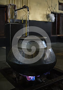 Big metal and oriental vessel stands above fire