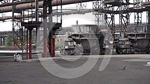 Big metal vats moved on carts outdoors at metallurgical plant. Stock footage. Iron and steel factory and production.