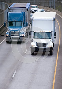 Big and middle rigs semi trucks driving on turning overpass road