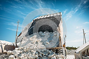 Big mining truck unloads mined ore or chalk or limestone. View from back