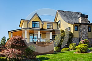 Big modern custom made luxury house with nicely landscaped front yard in summer. Beautiful house entrance with a garden