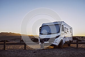 Big motorhome camper parked off road with desert and blue sky in background. Travel lifestyle camping car and freedom. Van against