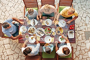 Big multigenerational family dinner in process.  Table with food and hands. Food consumption and multigenerational family Top view