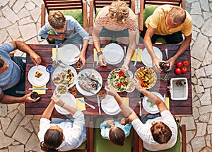 Big multigenerational family dinner in process. Top view image on table with food and hands. Food consumption and