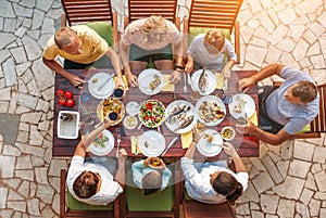 Big multigenerational family dinner in process. Top view image on table with food and hands. Food consumption and