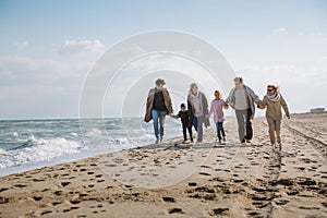 big multigenerational family walking together on beach